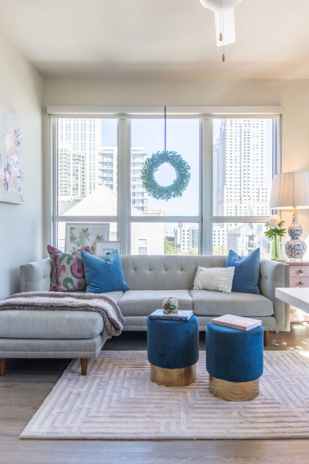 Apartment living room Christmas tree holiday decor with pink and blue, maze rug, velvet stools, and tan sectional by Kevin O'Gara on Thou Swell #apartmentstyle #apartmentdesign #apartmentdecor #livingroom #livingroomdesign #livingroomdecor #christmastree #holidaydecor #christmastyle #homedecorideas